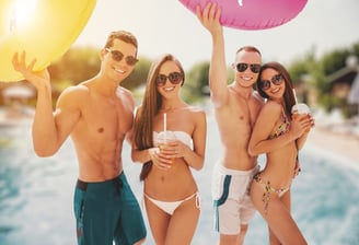 Group of stylish friends in swimwear at a Vegas pool party, showing ideal dayclub dress code