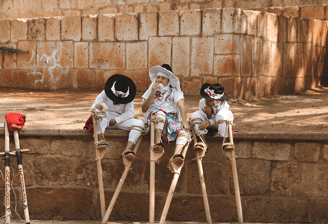 narrativa cultural: three children in white dresses and hats sitting on a ledge