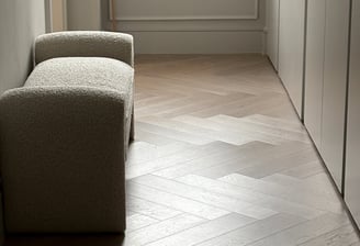 A light oak herringbone floor with a small chair