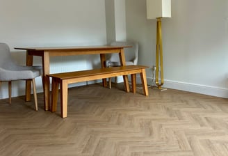 A medium oak colour herringbone LVT floor with a table and chairs