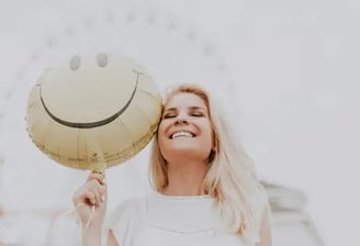 Mulher sorridente segurando um balão de emoji feliz