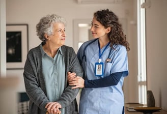 A nurse converses with an elderly woman in a hospital hallway, providing care and support.