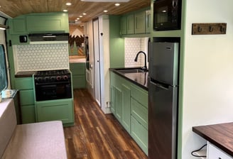 kitchen inside a schoolie bus with a refrigerator, stove, and large sink