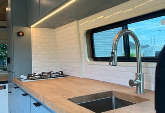 wooden countertop with beautiful backsplash inside van with sink and stovetop