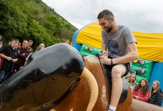 A man riding a rodeo bull at Cwmdu and District Show infront of a crowd