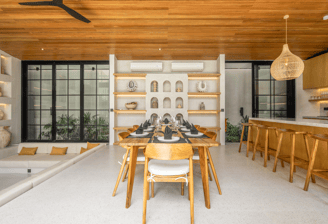 Dining table set in between a sunken lounge and kitchen island with bar stools