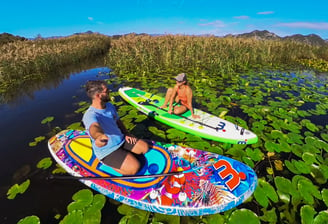 two people are sitting on paddle boards in the water