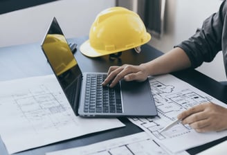 Computador com um capacete de engenharia na mesa