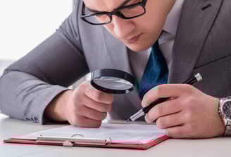 homem com uma lupa inspecionando um documento