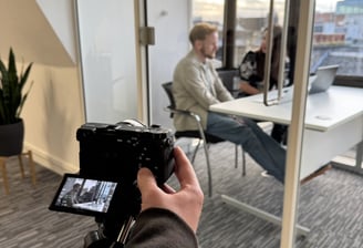 a person holding a camera and taking a picture of a man in a chair
