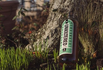 a bottle of whisky sitting on the ground next to a tree