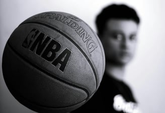 a man holding a basketball ball in front of a wall