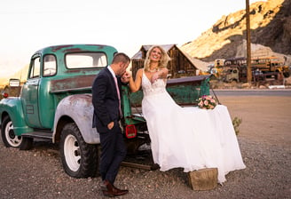 a bride and groom standing in front of a truck