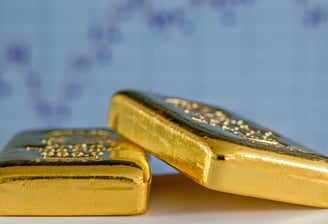 gold bullion bars on flat surface with charts in background