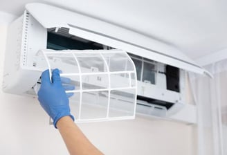 a person in gloves and gloves is holding a filter white of a air conditioner