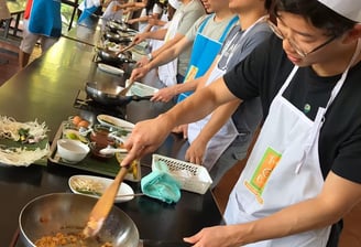 a group of people participating in thai cooking classs