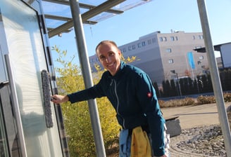 Ein glücklicher Fensterputzer reinigt in der Sonne ein Fenster. 