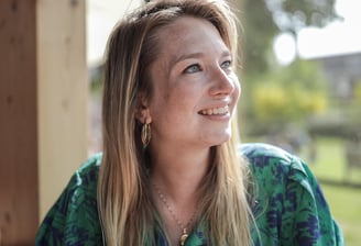 Een vrouw zit aan een tafel met een kop koffie.