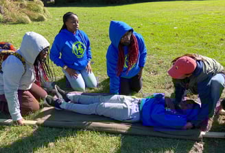 Youth learning to make a stretcher with a blanket and sticks