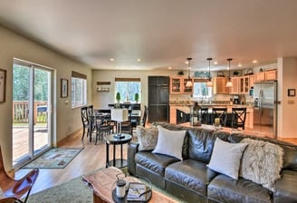 Open-concept living room and kitchen with leather sofa, dining area, and deck access at Moose Creek.