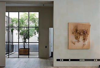 Vista frontal de salón con grandes ventanales, interruptores de diseño y planta natural integrada