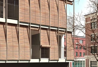 Proyecto residencial con revestimientos de madera y grandes terrazas protegidas con celosías metálicas