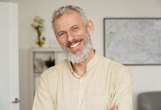 A cheerful older man with a beard smiling confidently, representing positivity and health.