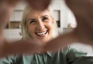 A cheerful older woman smiling, heart gesture, symbolising positivity, ageing gracefully