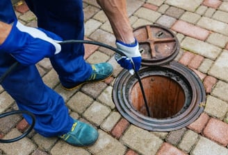 plumber cleaning a sewer line with a hose pump