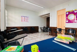 a classroom with a table and chairs and a clock