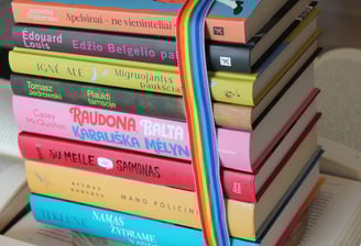a stack of books with a rainbow - colored ribbon tied to a book