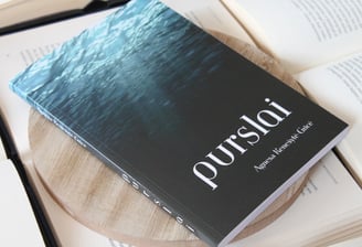 knyga purslai a book with a bookmark on it and a book on top of a wooden