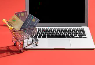 Mini chariot avec des cartes bancaires devant un ordinateur portable.