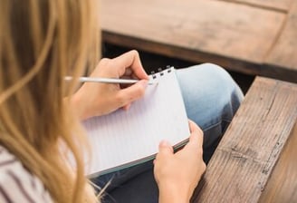 Personne prenant des notes dans un cahier.