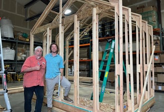 two men standing in front of a house construction showing the iwood wooden frame