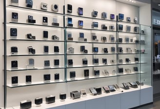 A bustling market stall is filled with a wide array of mobile phone cases and accessories, displayed on shelves and racks. Several people are browsing the items, dressed warmly for the weather. The cases come in various colors and designs, adding vibrancy to the scene.