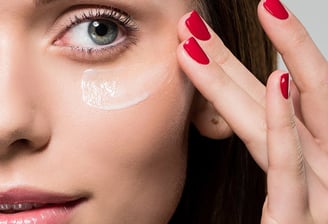 Frau verstreicht Creme auf Wange