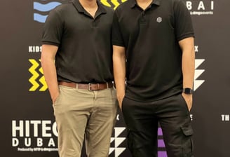 two men standing next to each other in front of a black and white sign