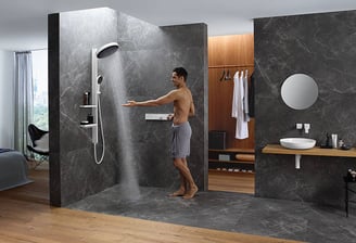 a man standing in a bathroom with a shower head