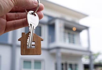 a person holding a keychain with a house keychaik