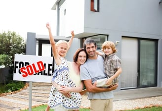 a family standing in front of a sold sign