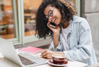a woman sitting at a table with a laptop and a cup of coffee
