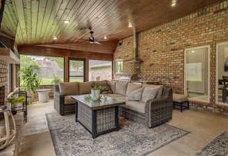 A photo of a screened porch with outdoor kitchen and living area