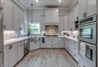 A photo of a remodeled kitchen with light cabinets and wooden floors.