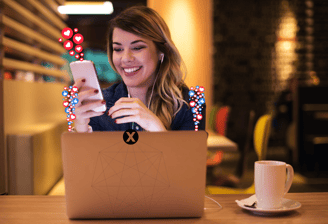 a woman sitting at a table with a cell phone and a laptop with social media icons