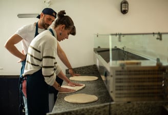 Femme qui apprend a faire des pizzas avec son professeur