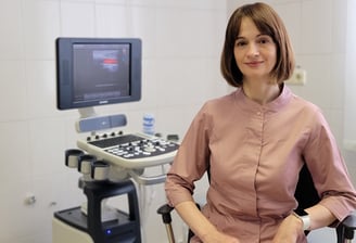 A doctor sits behind an ultrasound machine.