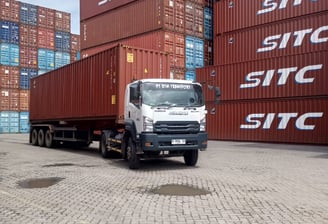 a truck with a trailer parked in front of a large container
