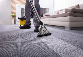 a man cleaning a carpet with a vacuum
