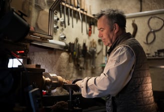 Artisan travaillant soigneusement une pièce de bois sur un tour à bois dans son atelier. L'atmosphèr